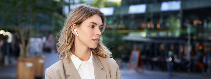 Portrait of young woman standing in city