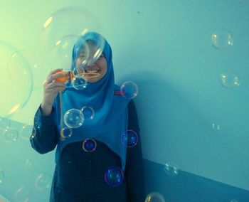 Happy woman blowing bubbles indoors
