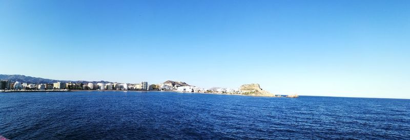 Sea by buildings against clear blue sky