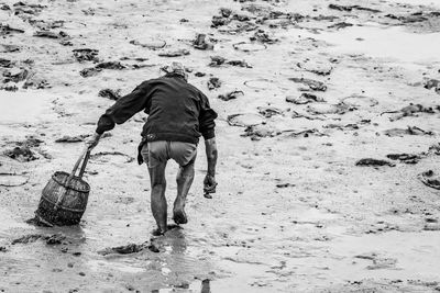 Rear view of man walking with dog on beach