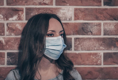 Portrait of young woman against brick wall