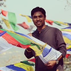 Portrait of smiling young man holding prayer flags