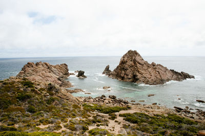 Scenic view of rocks in sea against sky