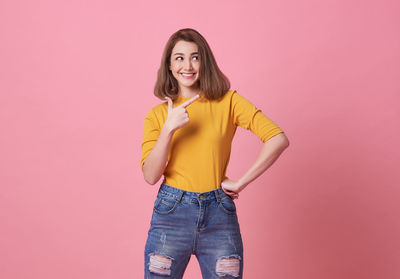 Portrait of a smiling young woman against pink background