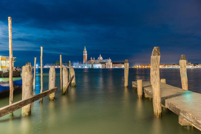 Wooden posts in sea at night