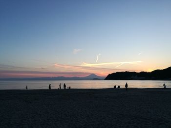 Silhouette people on beach against sky during sunset