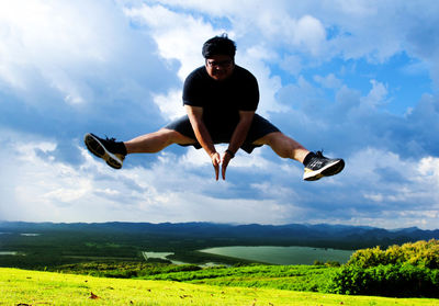 Full length of man jumping on field against sky