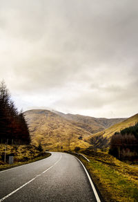 Country road against cloudy sky