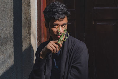 Portrait of young man holding flower