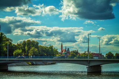 Bridge over river in city against sky