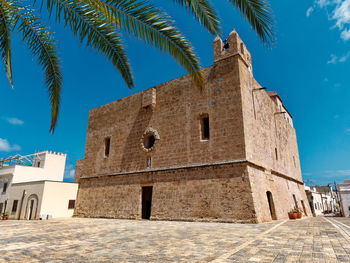 Low angle view of palm trees and building against sky