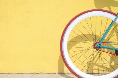 Close-up of bicycle parked by yellow wall