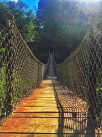 Footbridge amidst trees against sky