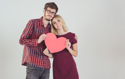 Young couple holding heart shape against white background