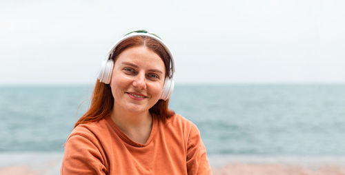 Portrait of woman wearing headphones at beach