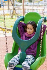 Girl sitting on swing in playground