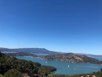 Scenic view of sea and mountains against clear blue sky