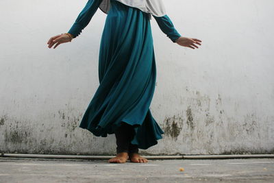 Low section of woman in traditional clothing standing by wall