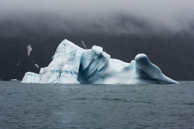 Iceberg in sea against mountains