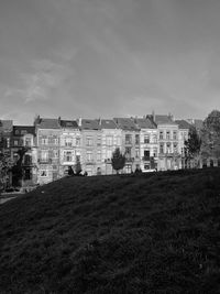 Front view of a few historical buildings in the middle of a public square full of greenery.