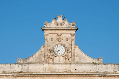 Low angle view of clock tower against blue sky in ostuni apulia