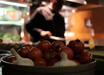 Close-up of fresh tomatoes with garlic bulbs in container at kitchen counter