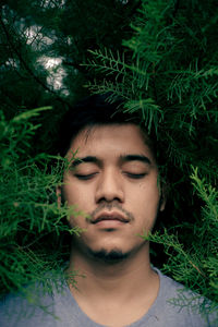 Young man with eyes closed amidst plants