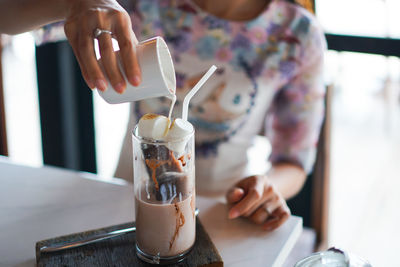 Midsection of woman preparing drink at table