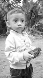 Cute baby boy holding toy while standing on land