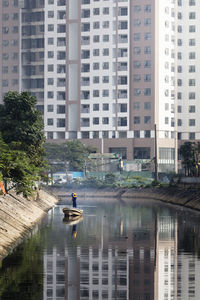People in river against buildings in city