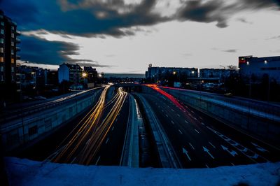 Light trails on road in city against sky at night