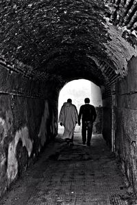 Rear view of people walking in tunnel