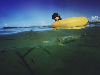 Portrait of boy with inflatable ring at sea against sky