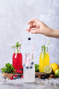 Close-up of person preparing fruits juices in glass jar on table