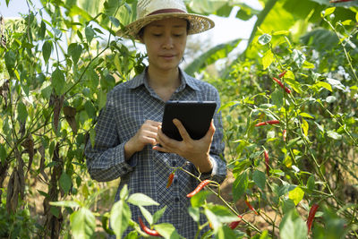 Full length of man holding mobile phone in farm