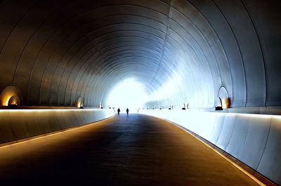 People walking in illuminated tunnel