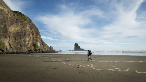 Full length of man walking on beach against sky