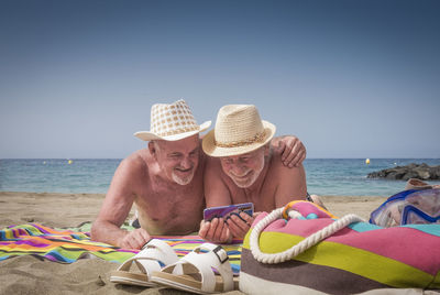 Men wearing hat on beach against clear sky