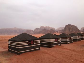 Deck chairs on desert against sky