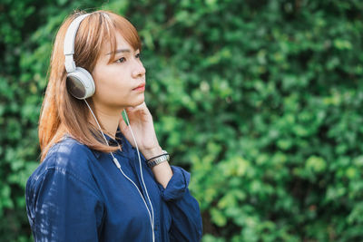 Young woman listening music while looking away in park