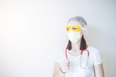 Portrait of teenage girl wearing mask against white background