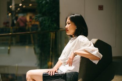 Side view of beautiful woman sitting in shopping mall