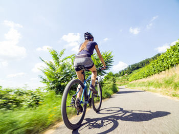 Man riding bicycle on road against sky