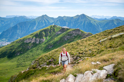 Woman hiking at mountains against sky