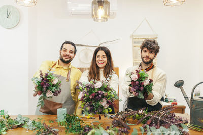 Smiling florists holding bouquets standing at floral shop