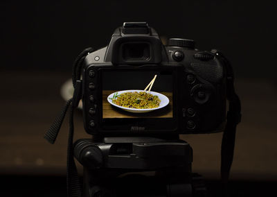 Close-up of camera on table against black background