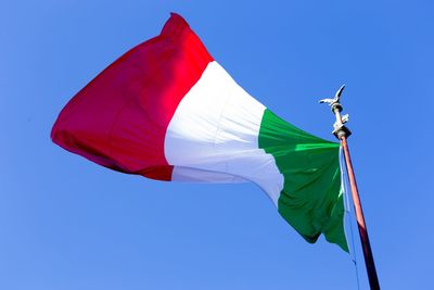 Low angle view of italian flag waving against clear blue sky