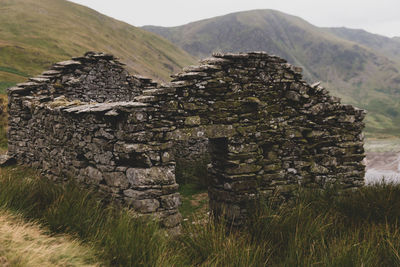 Stone wall on field against mountain range