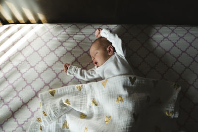 High angle view of cute baby girl lying on bed at home