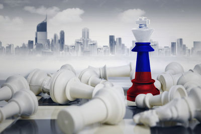 Digital composite image of chess pieces with flag against buildings in city